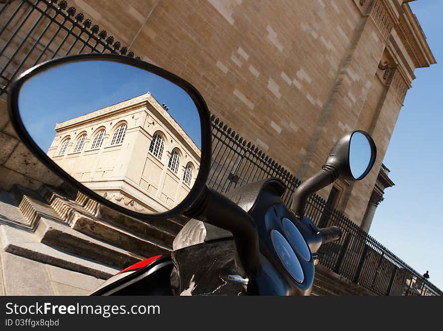 A historic building in Paris seen in a motorbike's rearview mirror. A historic building in Paris seen in a motorbike's rearview mirror