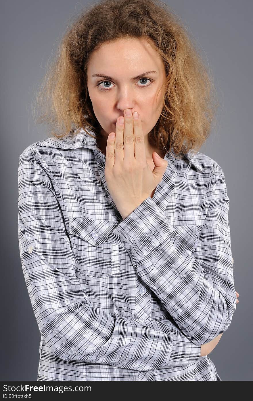 Young woman says ssshhh to maintain silence on a grey background