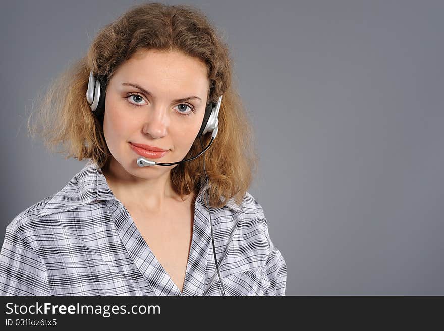 Young female customer service representative in headset, smiling on a grey background