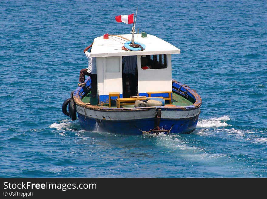 Old boat with cabin is sailing away, visible aft and Peruvian flag. Old boat with cabin is sailing away, visible aft and Peruvian flag