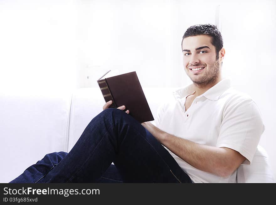 Young man reading book in home interior on white background