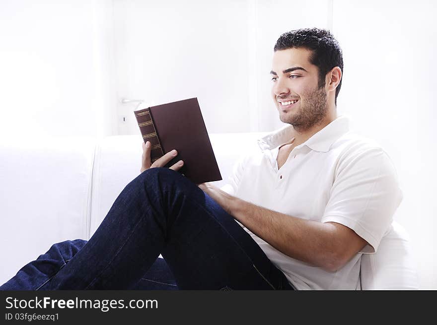 Young man reading book in home interior on white background