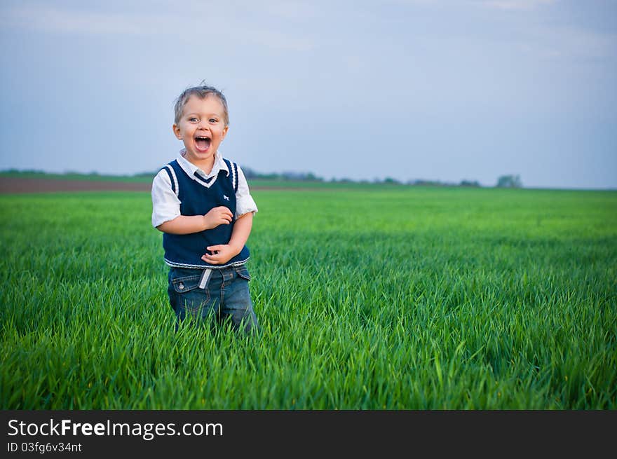 A beautiful little boy staing in the grass