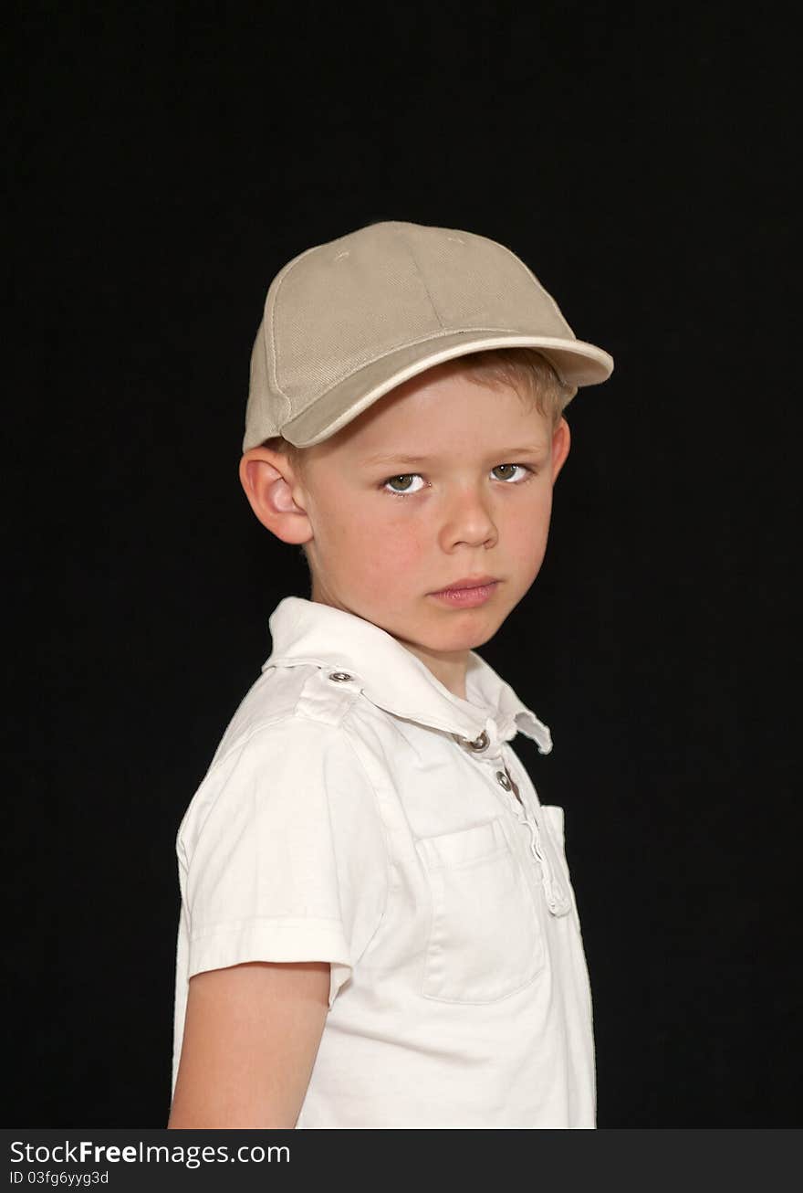 Adorable young boy in a baseball hat isolated on a black background