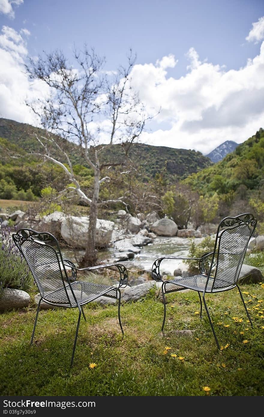 Two chairs near mountain quick spring river at sunny day