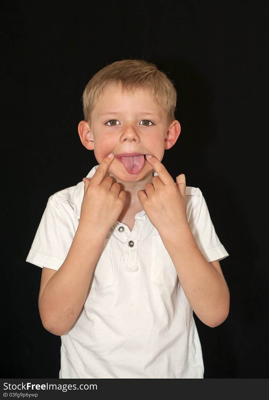 Adorable young boy pulling a funny face isolated on a black background