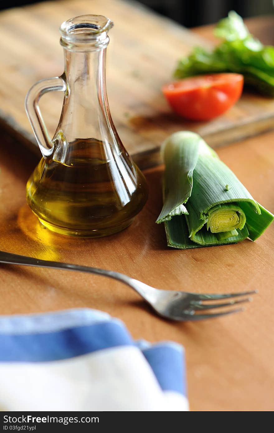 A bottle of olive oil and vegetables on the table. A bottle of olive oil and vegetables on the table