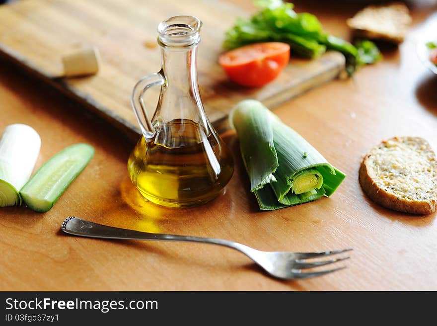 A bottle of olive oil and vegetables on the table. A bottle of olive oil and vegetables on the table