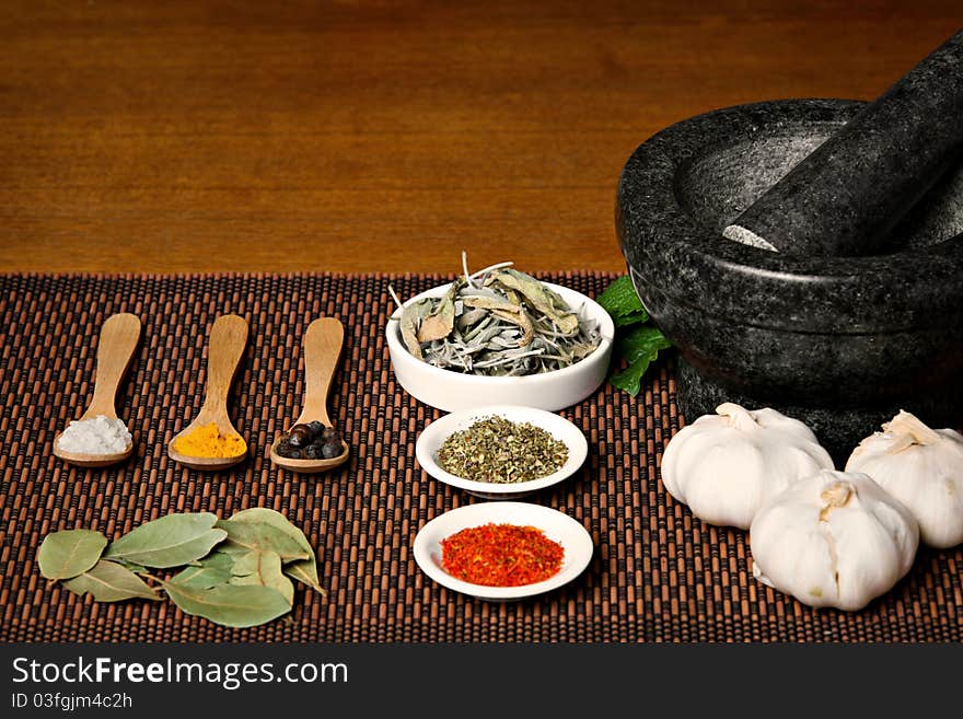 Different spices with wooden spoons and mortar on wooden table