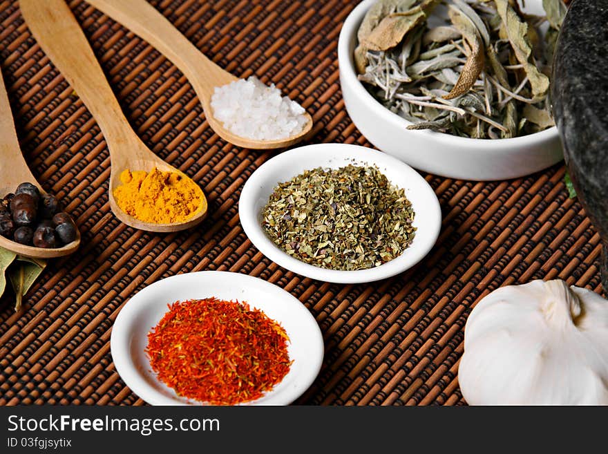 Different spices with wooden spoons and small ceramic plates