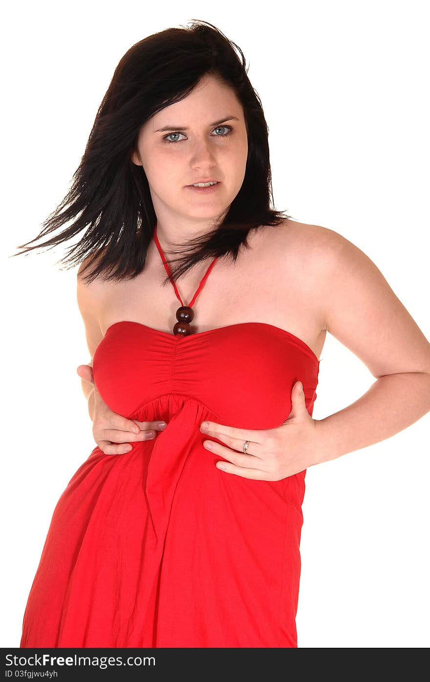 A beautiful young woman in a red dress standing in the studio and her black hair is blowing away, for white background. A beautiful young woman in a red dress standing in the studio and her black hair is blowing away, for white background.