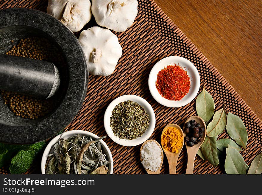 Different spices with mortar on wooden table