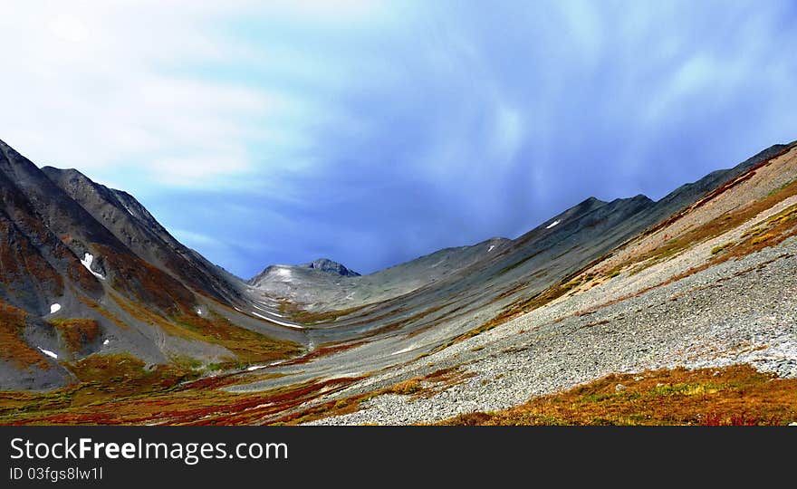 The uppers of the stony lifeless mountain valley in the background of the approaching bad weather. The uppers of the stony lifeless mountain valley in the background of the approaching bad weather