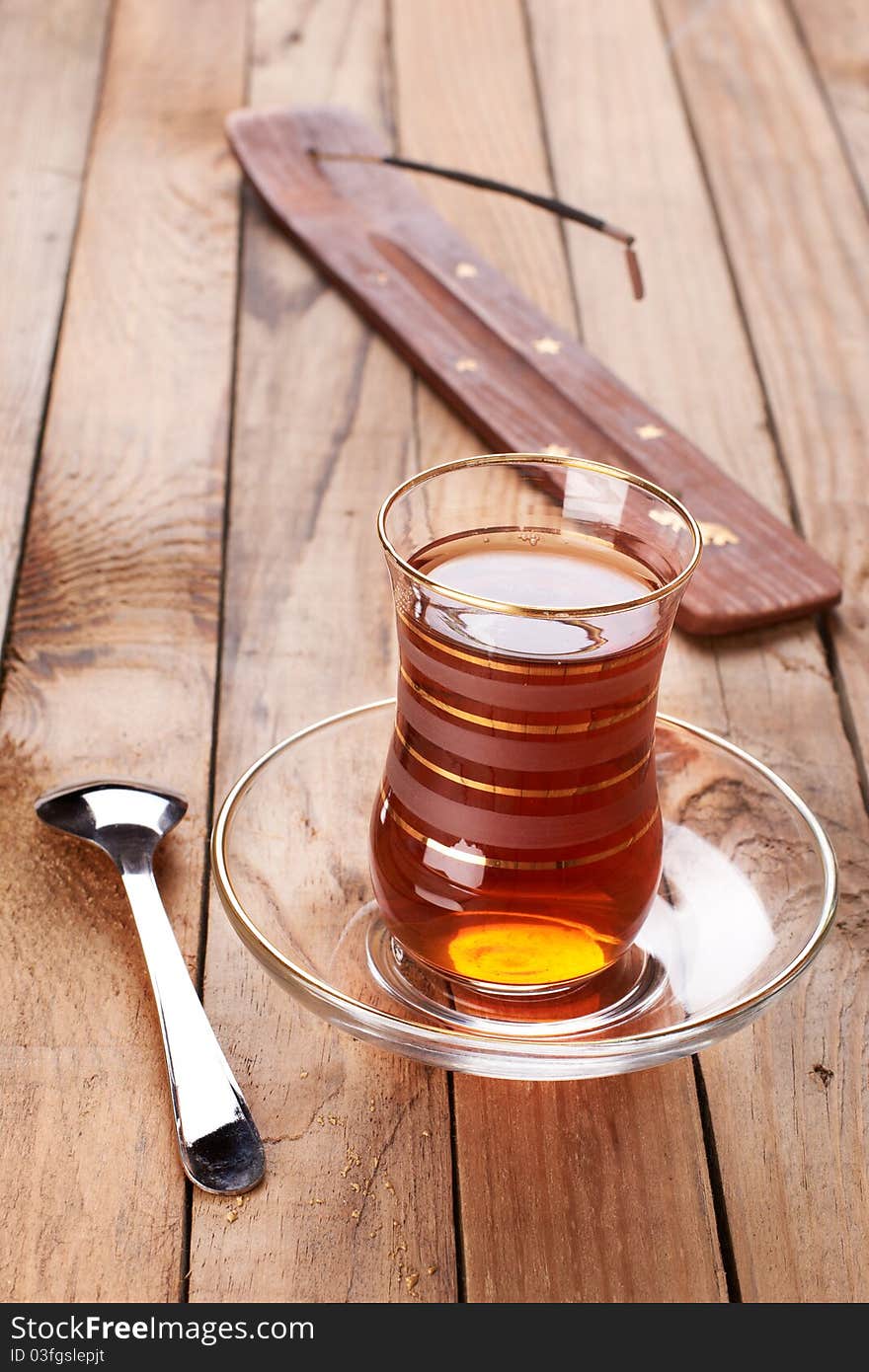 Turkish apple tea in traditional glass and plate on wooden background