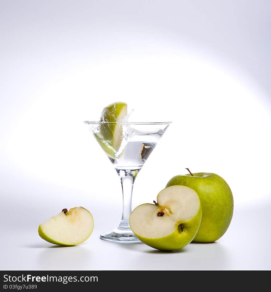 Apple cocktail splashing on a glass on white background. Apple cocktail splashing on a glass on white background