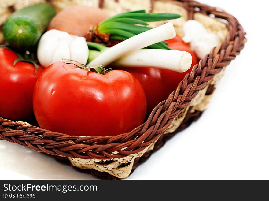 Tomatoes, cucumbers, green onions, garlic in a wicker basket isolated on white background. Tomatoes, cucumbers, green onions, garlic in a wicker basket isolated on white background..