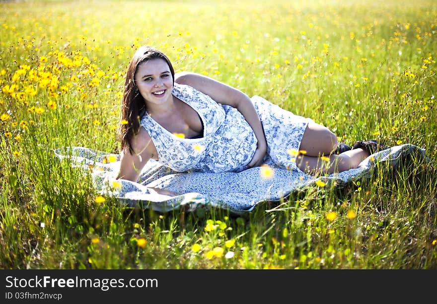 Happy, healthy pregnant woman in a field of yellow flowers touching her belly. Happy, healthy pregnant woman in a field of yellow flowers touching her belly.