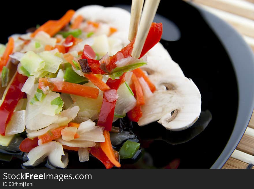 Chinese vegetables with chopsticks on a black plate. Chinese vegetables with chopsticks on a black plate