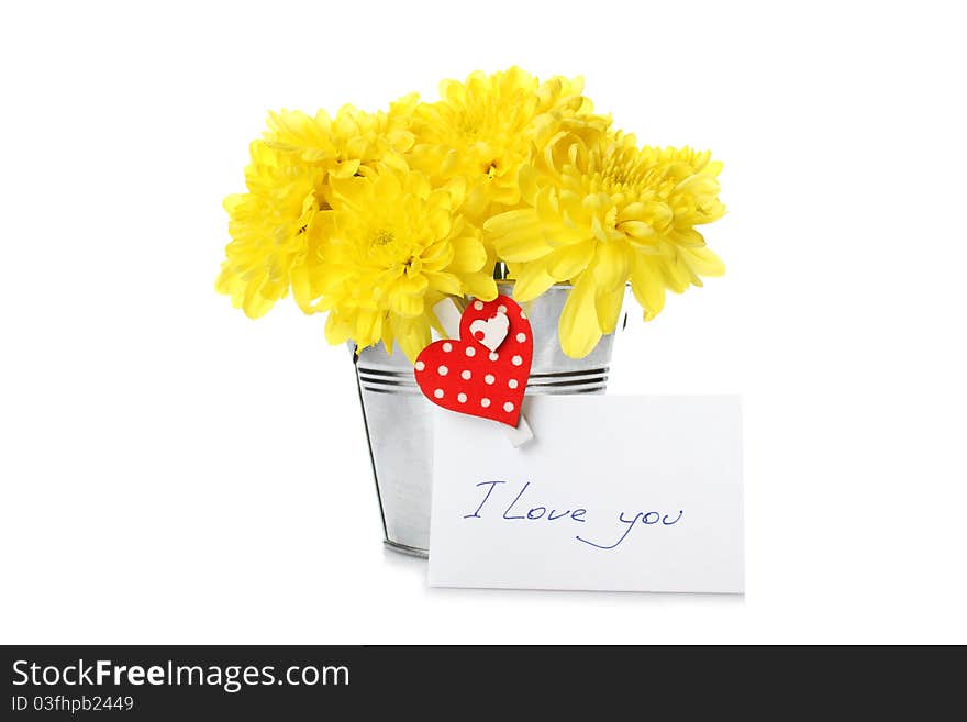 Yellow chrysanthemums in a bucket with chrysanthemums next card with the text I love you and a pin with a red heart. Isolated. Yellow chrysanthemums in a bucket with chrysanthemums next card with the text I love you and a pin with a red heart. Isolated