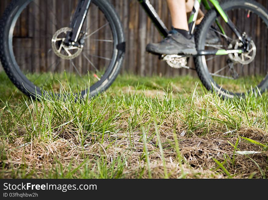 Mountain biker riding a bike in backcountry environment, blurred biker and focus on grass. Mountain biker riding a bike in backcountry environment, blurred biker and focus on grass