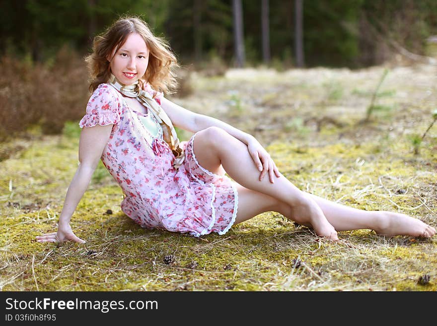 Sweet sexy woman in beautiful dress is sitting in a sunshine on a golden field near the forest. Sweet sexy woman in beautiful dress is sitting in a sunshine on a golden field near the forest