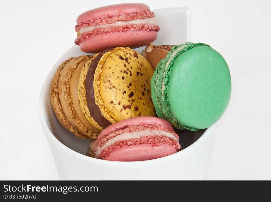 A selection of colourful macaroons in a cone-shaped white ceramic dish. A selection of colourful macaroons in a cone-shaped white ceramic dish