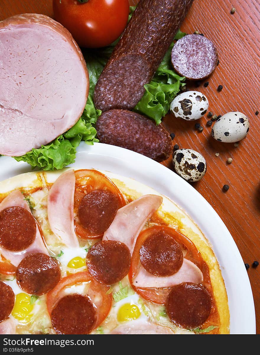 Pizza with salami, ham, edd and tomato, on a table