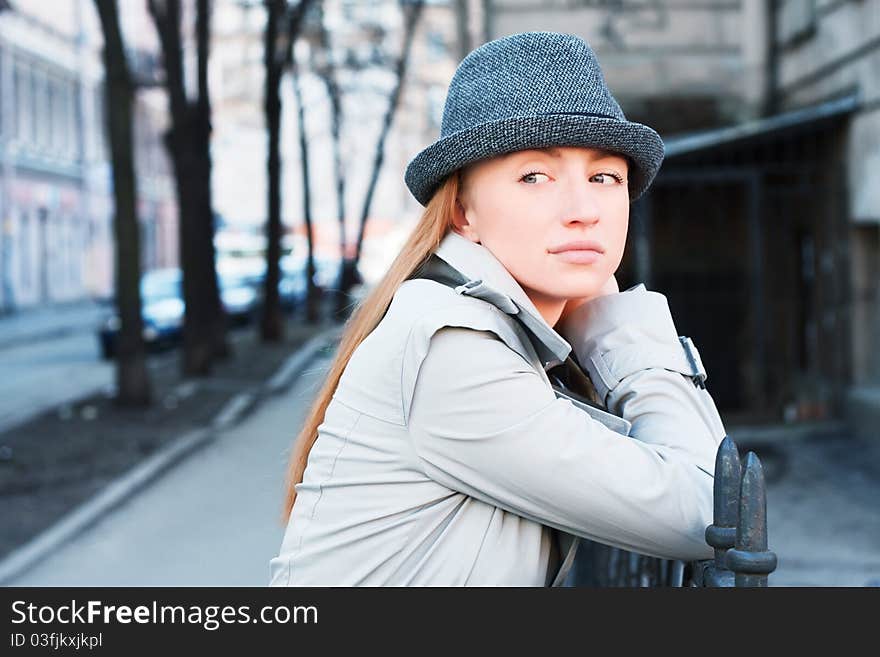 Beautiful young woman in a raincoat on the street