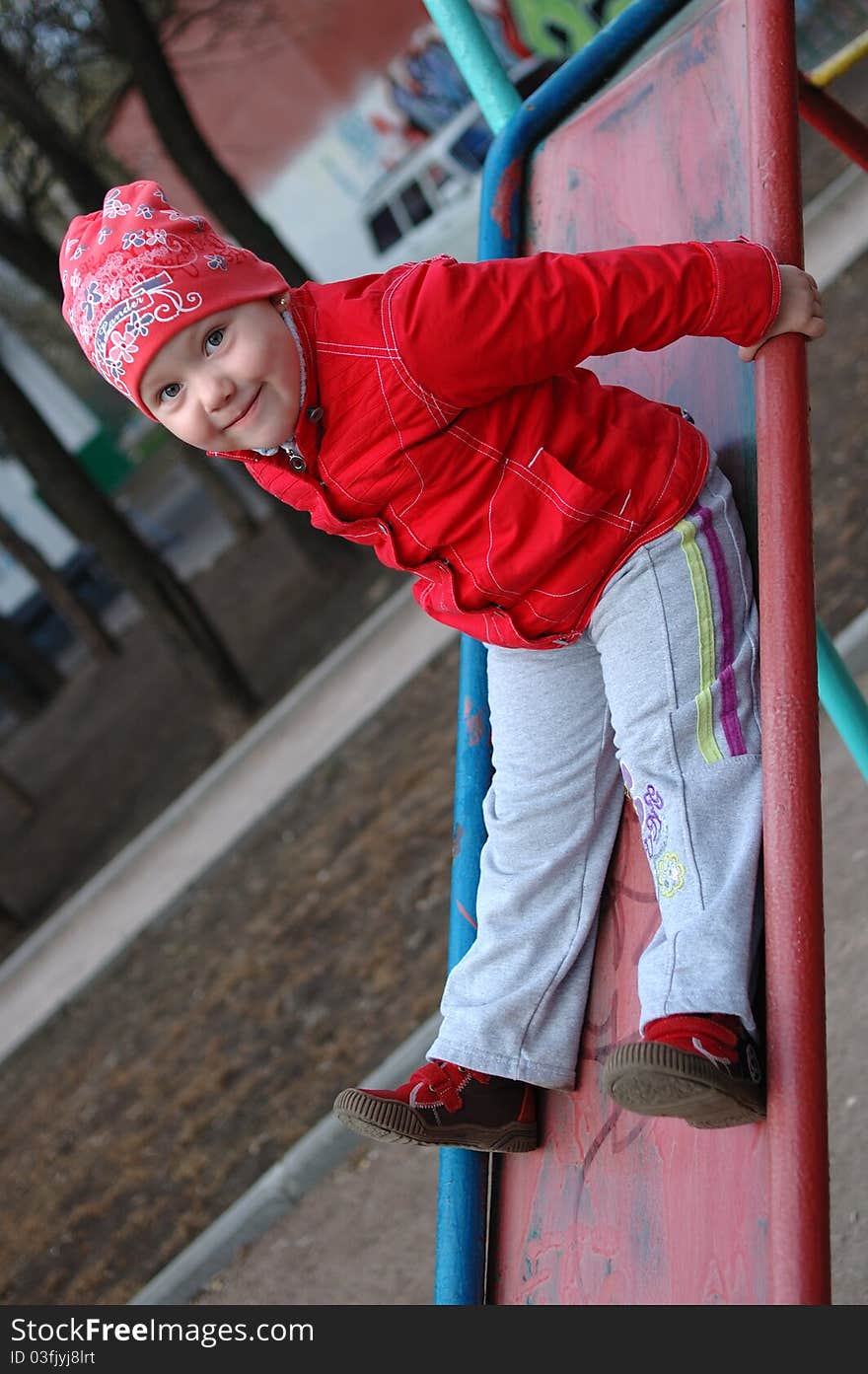 Pretty little girl play on the playground red slide. Pretty little girl play on the playground red slide.