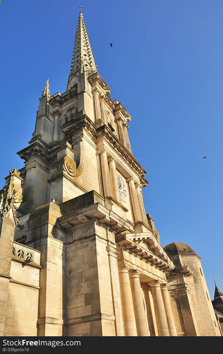 A French cathedral and its tall bell tower under a blue sky