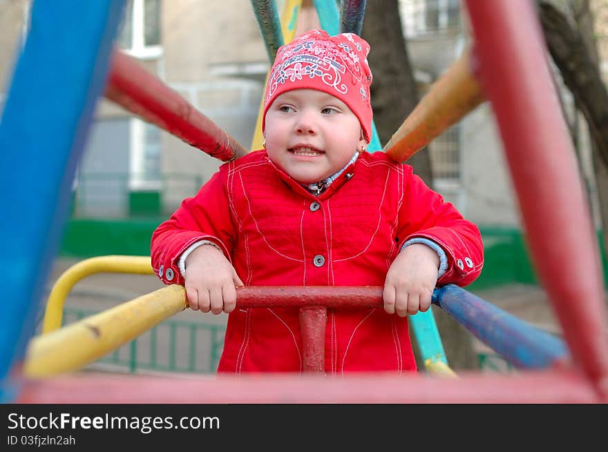 Pretty little girl play on the playground metal monkey bars. Pretty little girl play on the playground metal monkey bars.