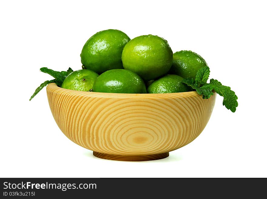 Fresh limes in wooden bowl, isolated on white