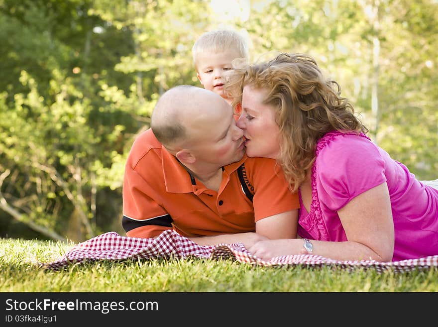 Affectionate Couple Kiss as Adorable Son Watches in the Park. Affectionate Couple Kiss as Adorable Son Watches in the Park.