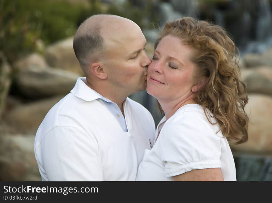 Happy, Attractive, Affectionate Couple Kiss on Cheek in the Park. Happy, Attractive, Affectionate Couple Kiss on Cheek in the Park.