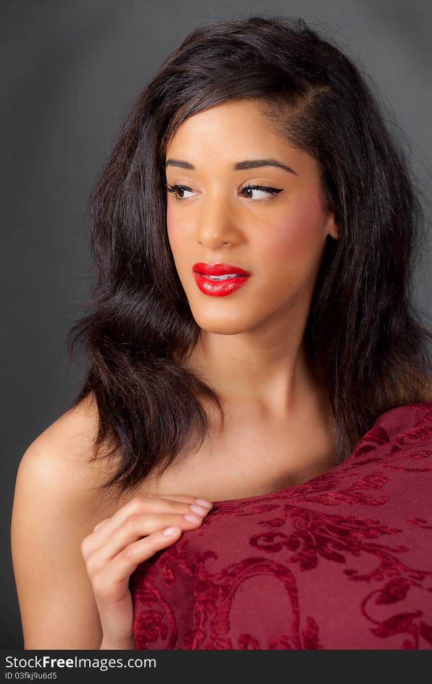 An implied nude portrait of a gorgeous young woman, leaning on red table and staring off into the distance. An implied nude portrait of a gorgeous young woman, leaning on red table and staring off into the distance