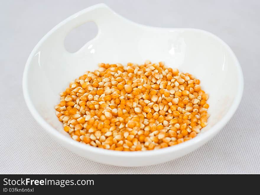 Pile of popcorn seeds isolated on white bowl