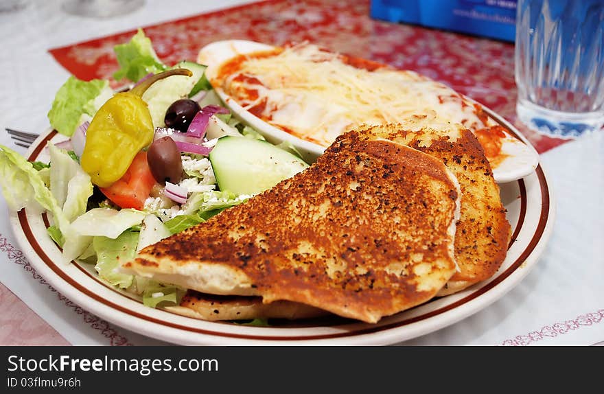 Greek salad on a white plate with bread and magaterenian food in restaurant. Traditional Greece food. Greek salad on a white plate with bread and magaterenian food in restaurant. Traditional Greece food.