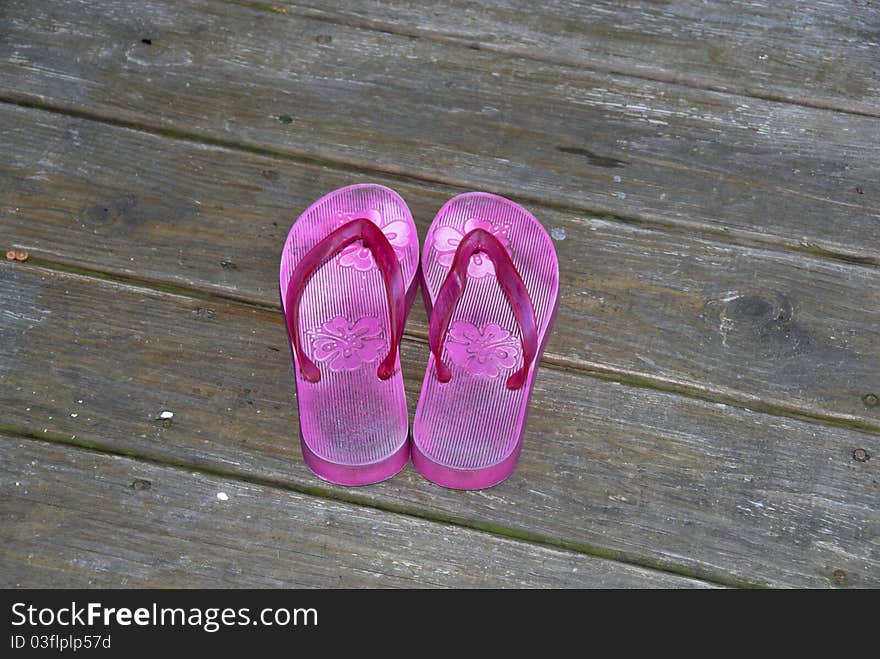 A pair of pink sandals by the pool deck