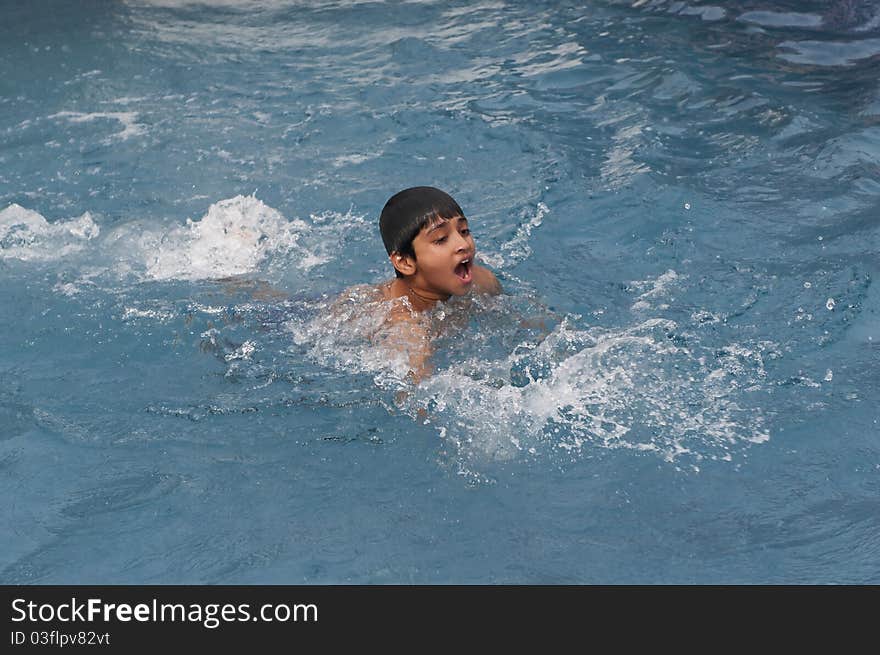 An handsome young indian kid swimming in the pool