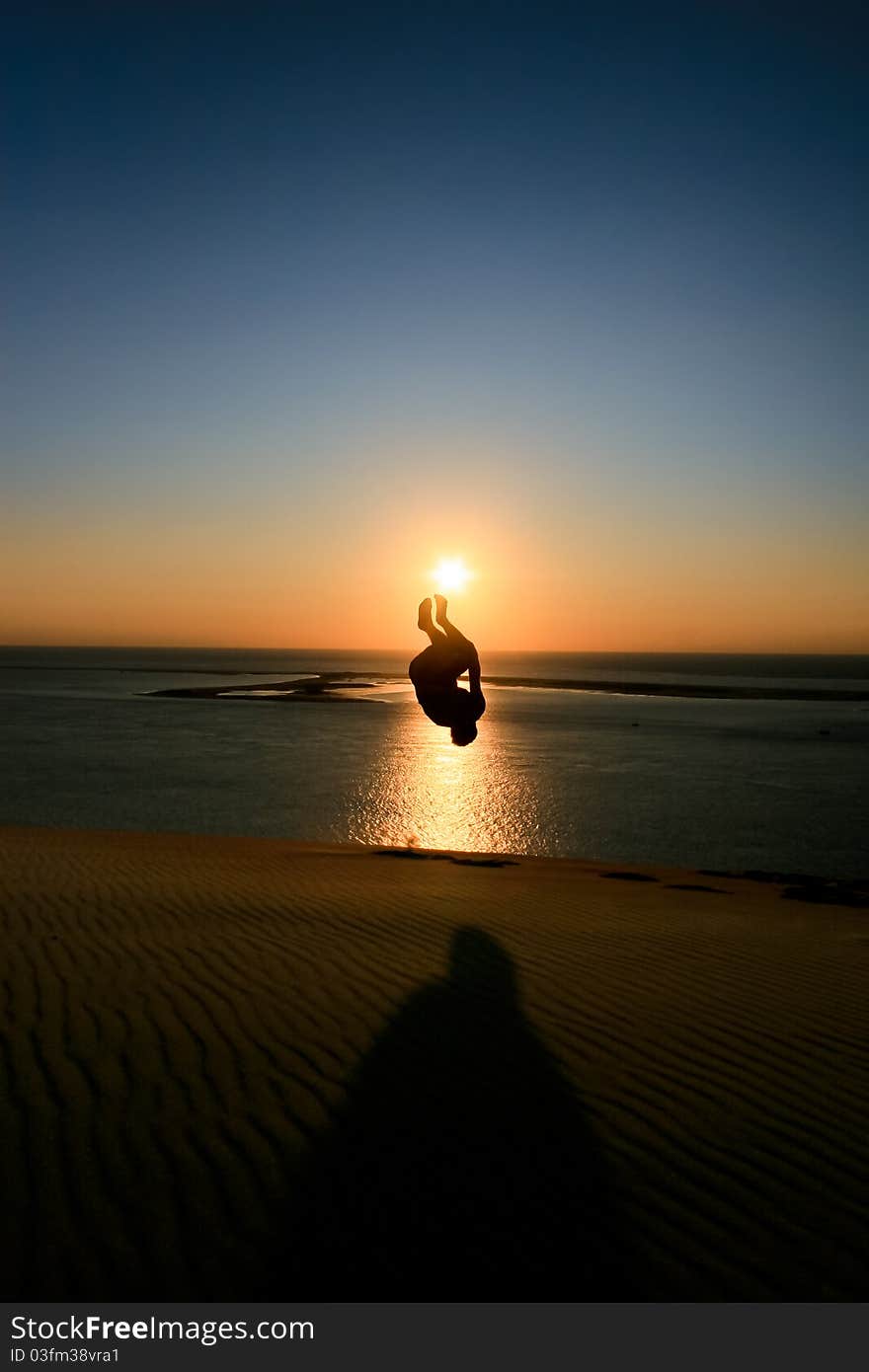 Silhouette of man jumping in sunset at beach