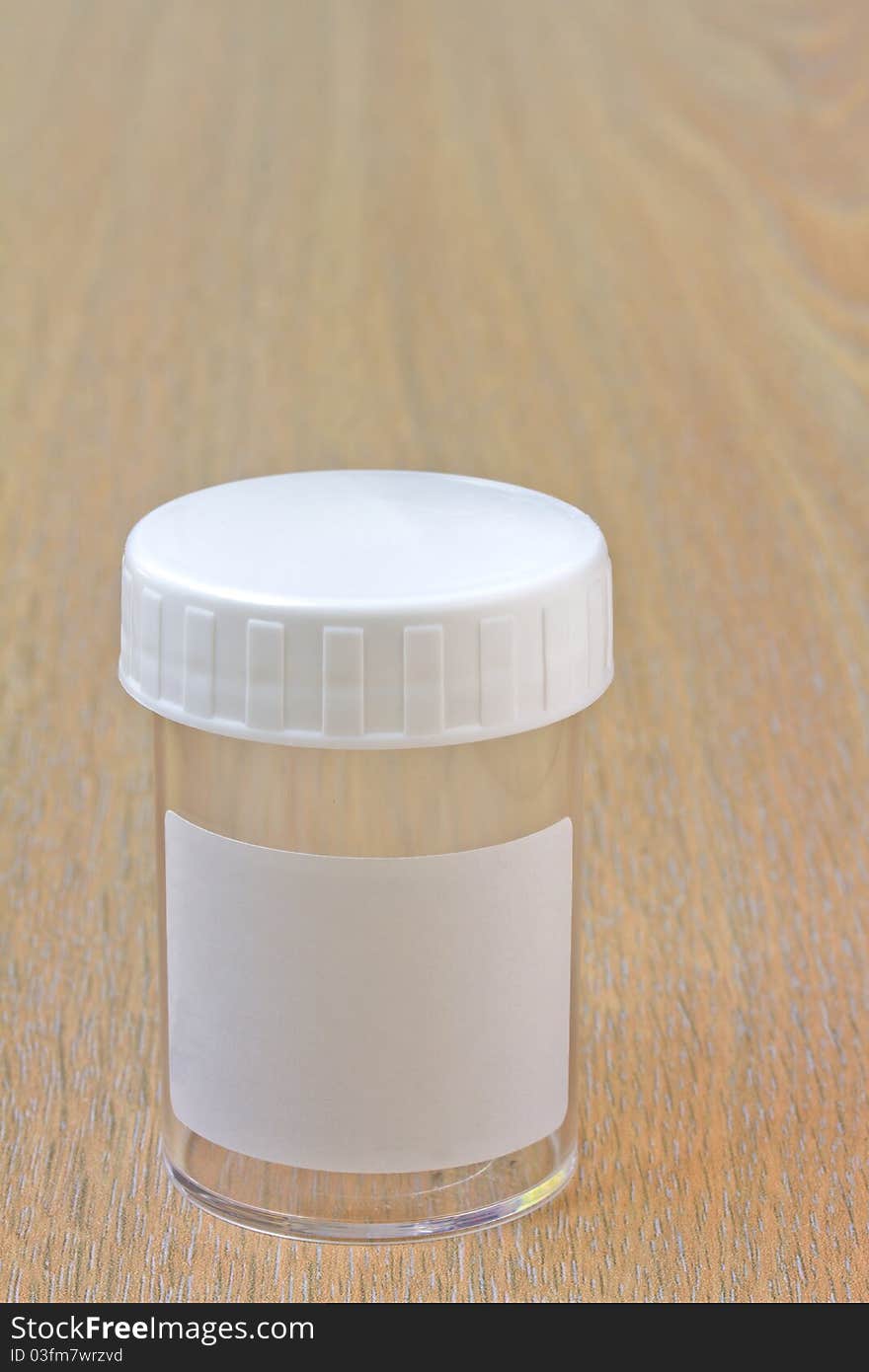 Empty plastic specimen bottle on wooden worktop. Empty plastic specimen bottle on wooden worktop