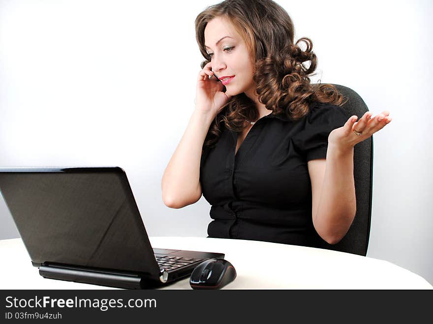 A beautiful caucasian businesswoman talking on the phone while working on her laptop