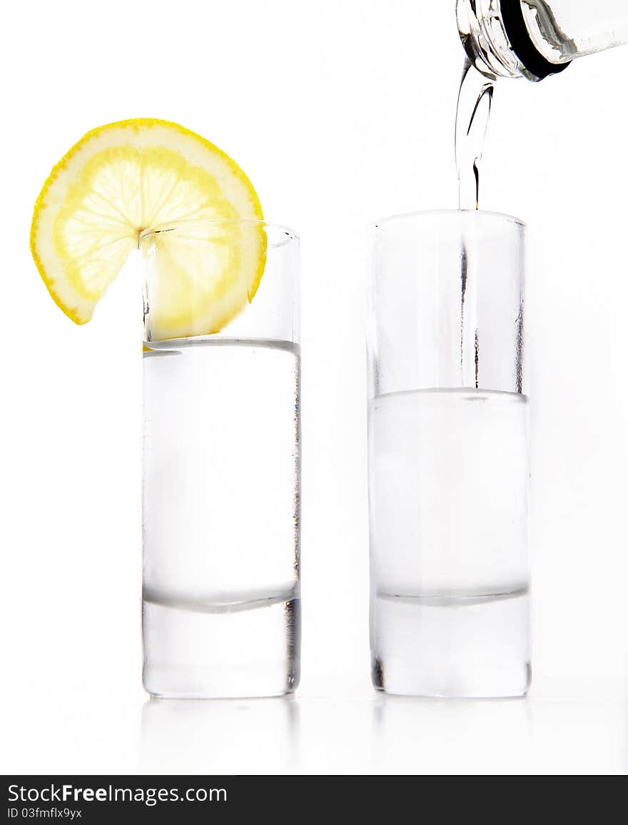 Two wine-glasses of vodka and lemon on a white background. Two wine-glasses of vodka and lemon on a white background