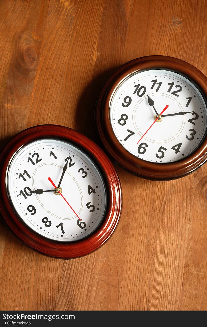 Pair of nice modern clocks on wooden surface. Pair of nice modern clocks on wooden surface