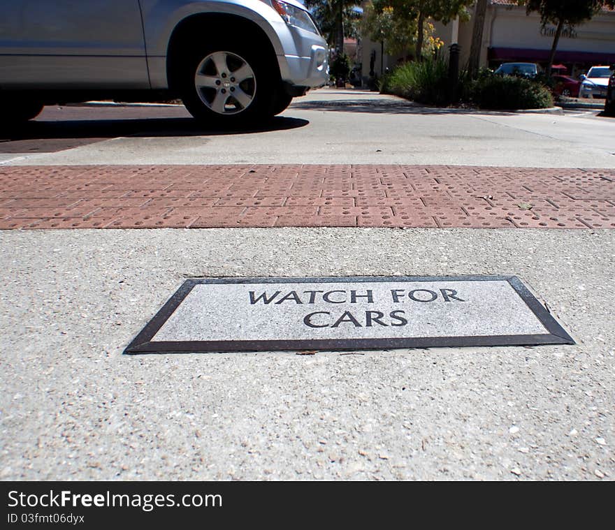 Sign at a crosswalk warning pedestrians of oncoming traffic ahead. Sign at a crosswalk warning pedestrians of oncoming traffic ahead