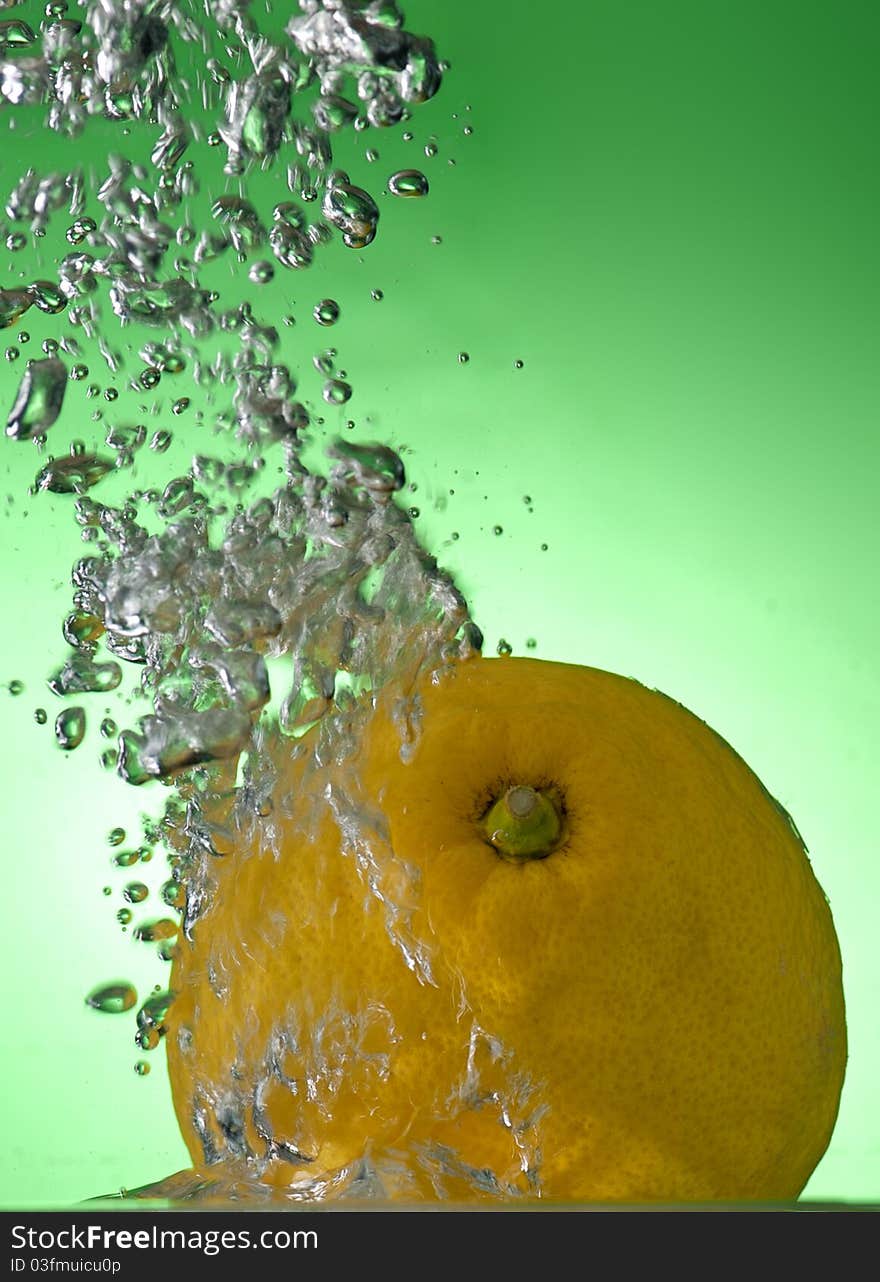 Lemon splash in water isolated on green. Lemon splash in water isolated on green