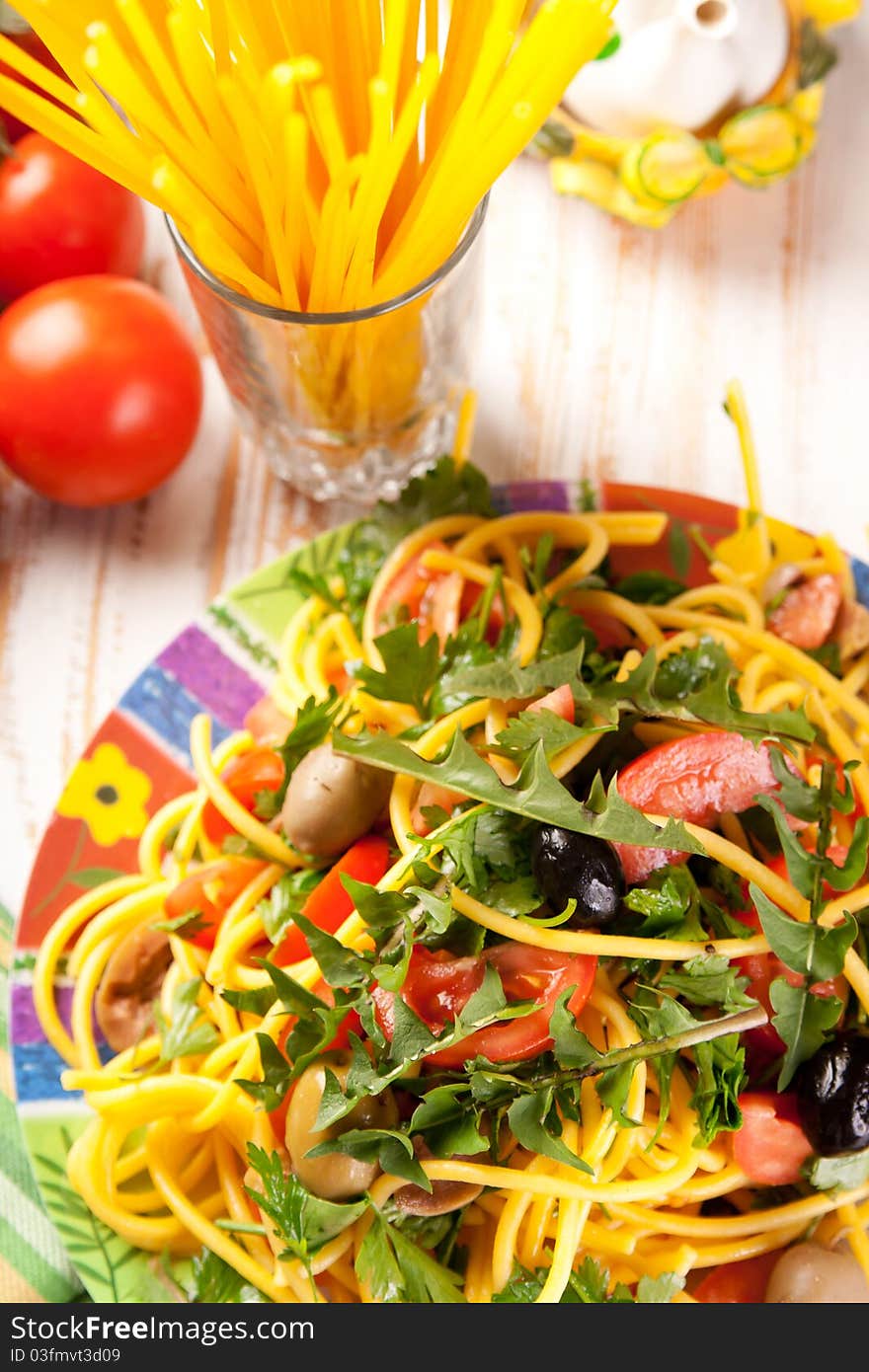 Plate of spaghetti with olives, tomatoes and herbs