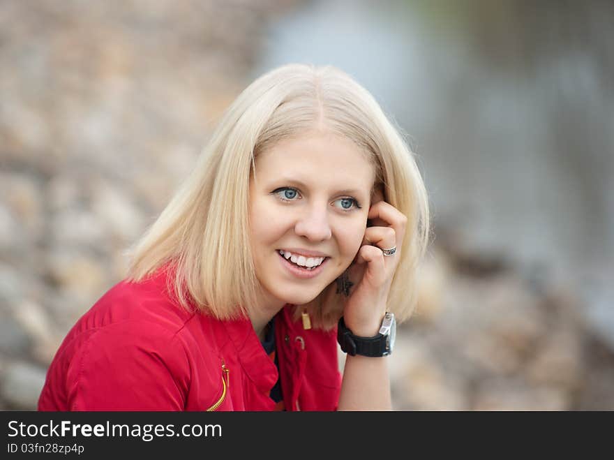 Attractive young girl sitting on a stones-beach near water