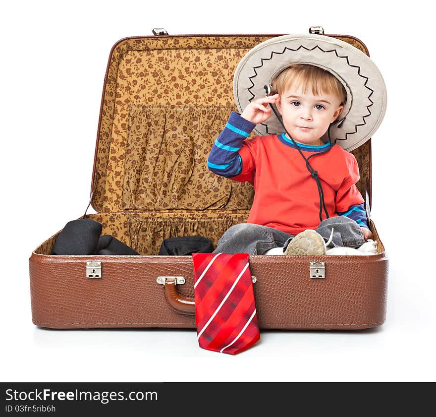 A funny boy with sombrero is sitting in the suitcase. Isolated on a white background. A funny boy with sombrero is sitting in the suitcase. Isolated on a white background