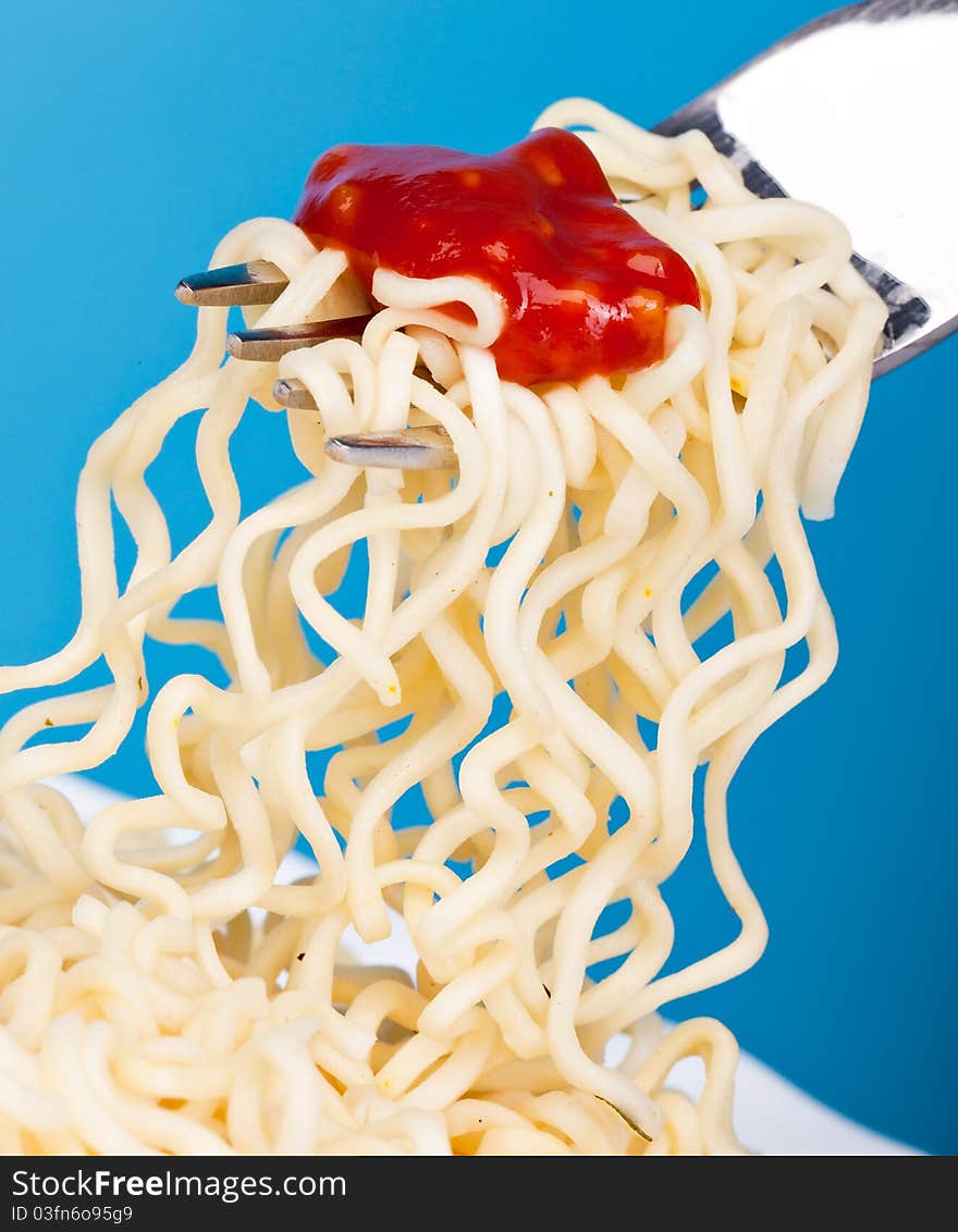 Vermicelli are on a fork on a blue bachground